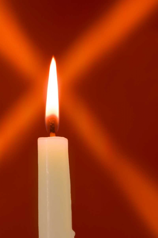 Burning candle with star burst on red background